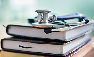 closeup of 2 books stacked with stethoscope lying on top of books