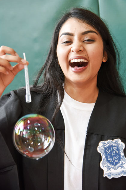 A student laughs as a bubble floats from the pipette she holds A woman laughs as a bubble floats from the pipette she holds