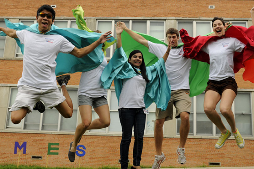 Students dress as vegetables at United to Serve. Five students leap into the air while wearing capes at United to Serve.