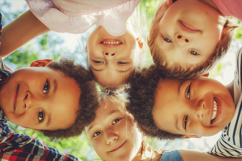 UT Southwestern offers on-campus child care options. Five young children put their heads together to form a circle while looking down at the camera