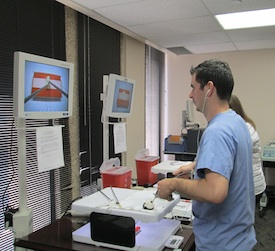 Resident practicing laparascopic techniques Man looking at screen while using surgical instruments