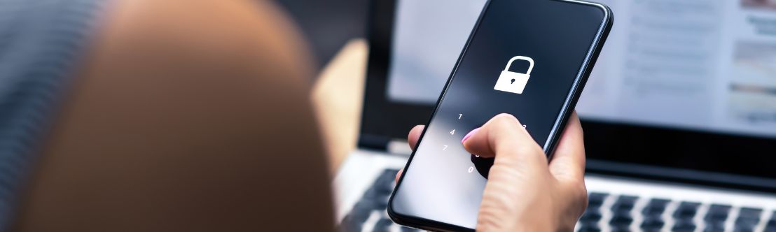 Locked cellphone screen in foreground, laptop in background