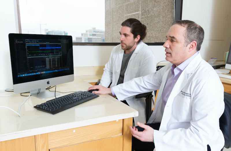 Graduate student Cody Ruhl and Dr. Michael Shiloh assess data at a computer