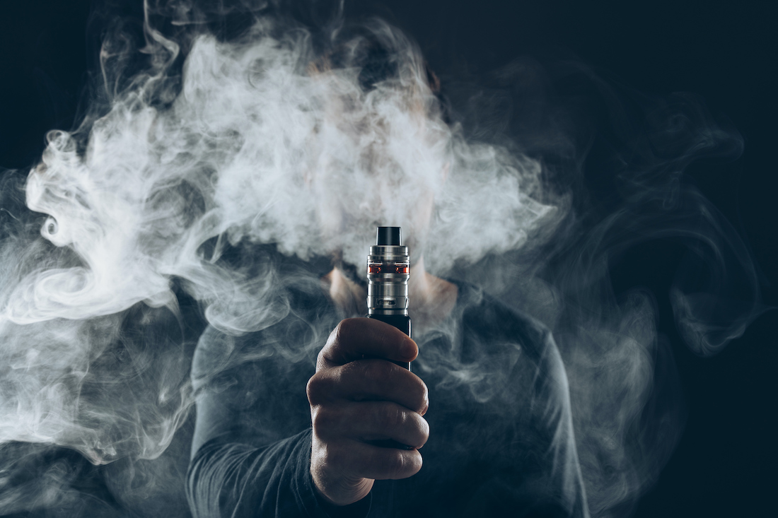 Man Holding Electronic Cigarette Against Black Background