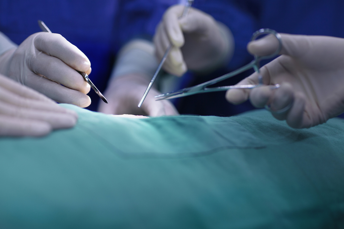 Hands of operating room staff performing surgery