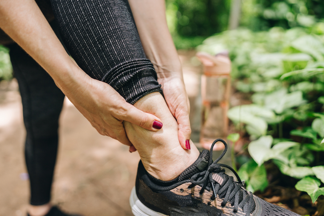 Close-up of woman with pain on ankle on the public park