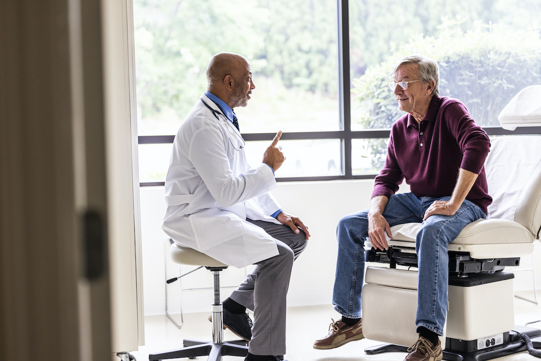 Male doctor talking with senior man in exam room