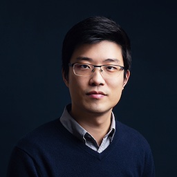 Dr. Ruan headshot: Asian man with rimless glasses, dark hair and dark blue v-neck sweater and dark background