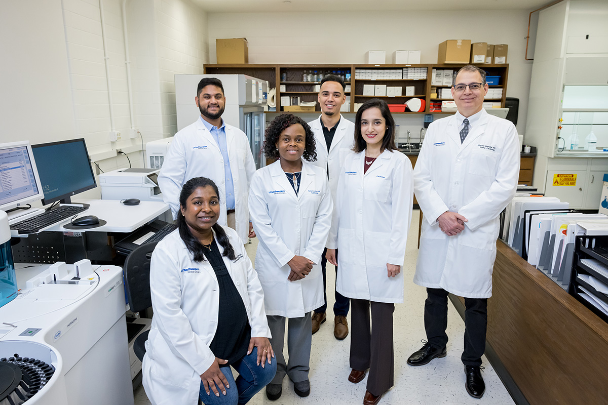 six members of the CMRU team wearing white lab coats standing in a laboratory