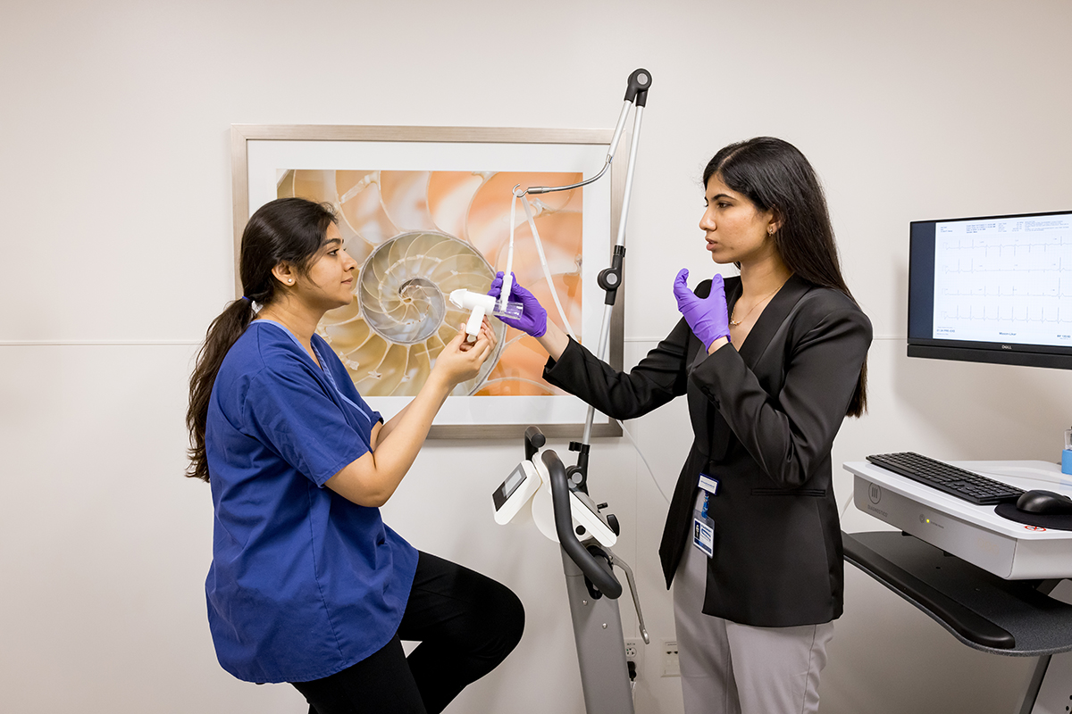 a woman on a stationary bike receiving instructions from the testing facilitator