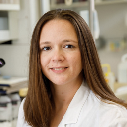 Dr. Amanda casey wearing a white lab coat standing in a laboratory