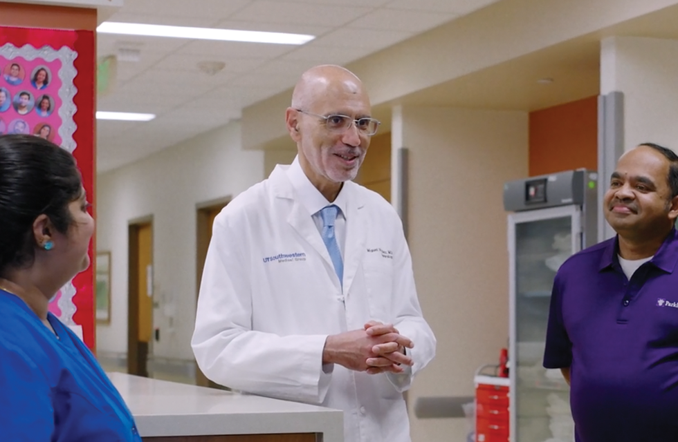 A male medical professional smiling at front desk at hospital